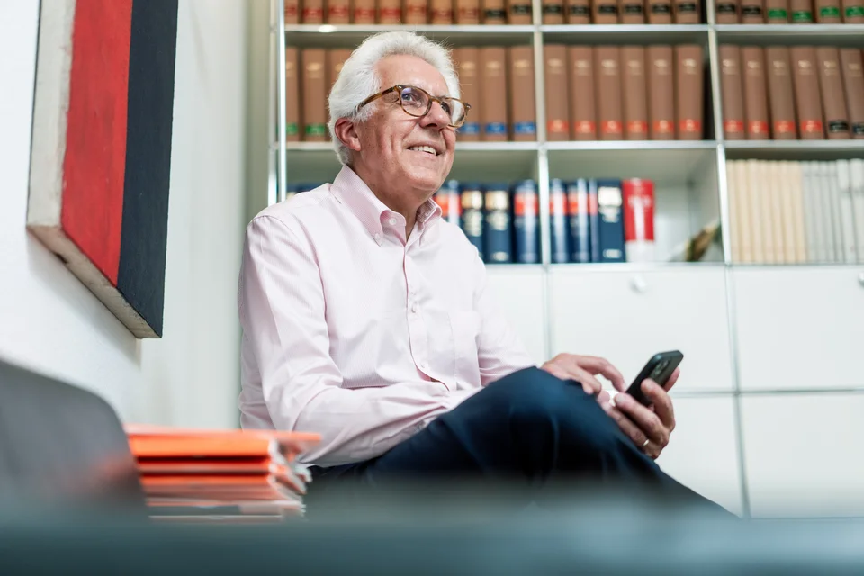 Thomas Salmen sitzt mit einem Handy in der Hand am Tisch